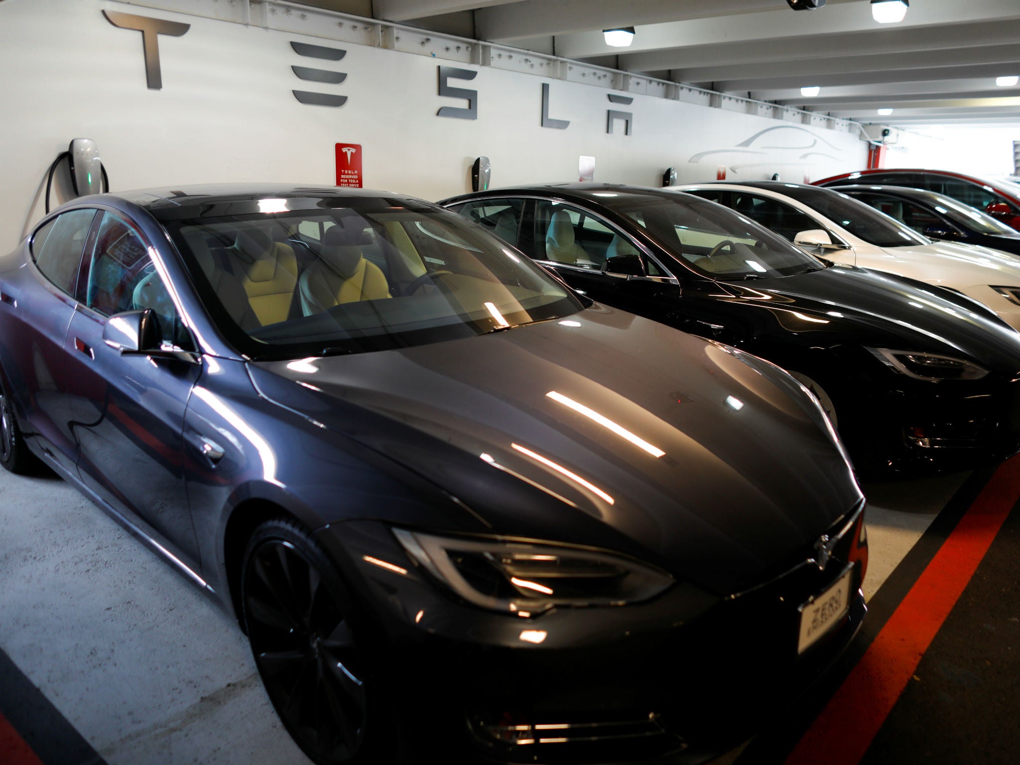 Tesla Model 3s and X's are shown charging in an underground parking lot next to a Tesla store in San Diego, California