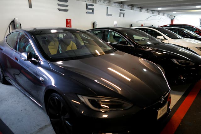 Tesla Model 3s and X's are shown charging in an underground parking lot next to a Tesla store in San Diego, California