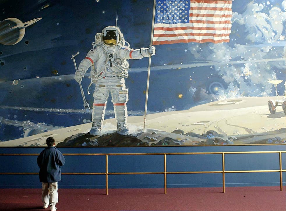 A boy looks at a wall-sized mural depicting an astronaut walking on the moon at the Smithsonian Air and Space Museum in Washington DC.