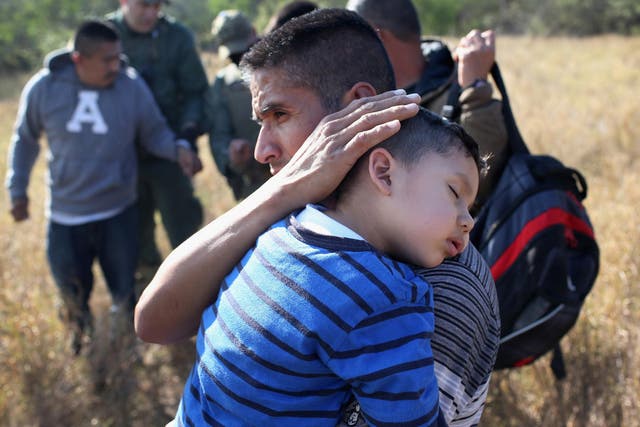 A father holds his sleeping three-year-old son, 3, after they were detained by Border Patrol agents near Rio Grande City, Texas