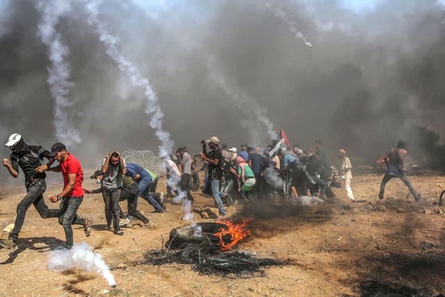 Palestinian protesters run for cover from Israeli tear-gas during clashes after Friday protests near the border east Gaza City, 8 June, 2018