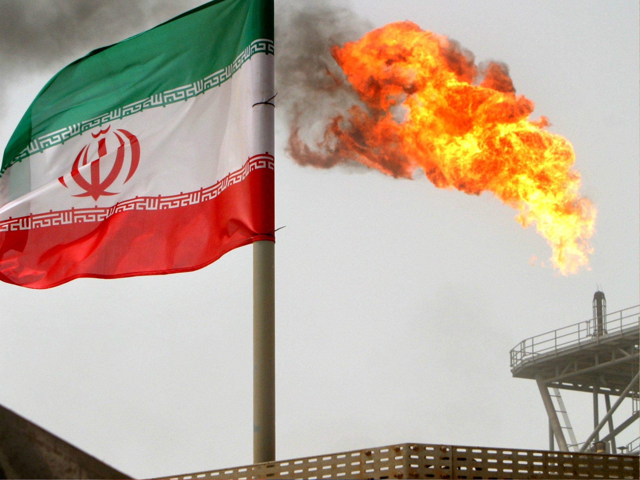 A gas flare on an oil production platform in the Soroush oil fields is seen alongside an Iranian flag.