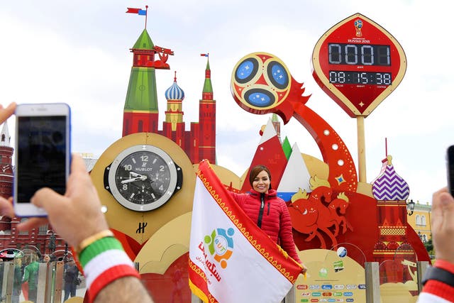 A woman poses for photos near a countdown board ahead of the football World Cup finals in Moscow on June 13, 2018.