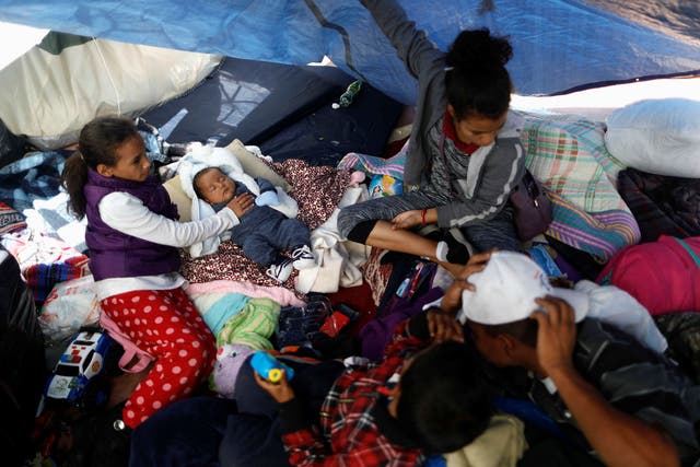 Children traveling with a caravan of migrants from Central America to the US are pictured under a plastic tarp at a camp near the San Ysidro checkpoint in Tijuana, Mexico