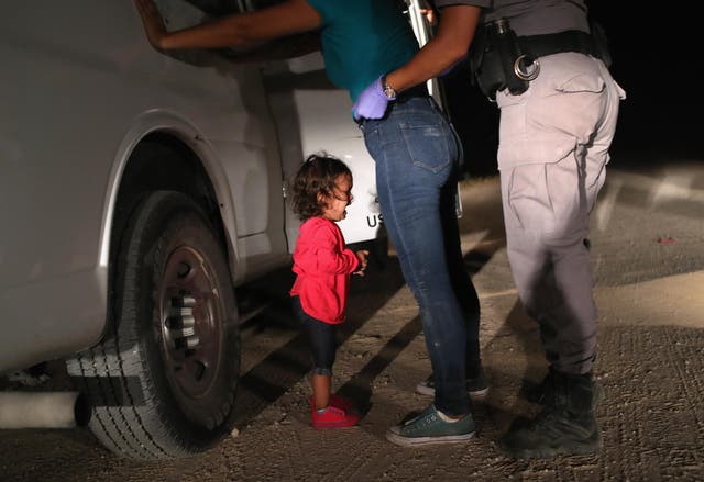 A two-year-old Honduran asylum seeker cries as her mother is searched and detained near the U.S.-Mexico border