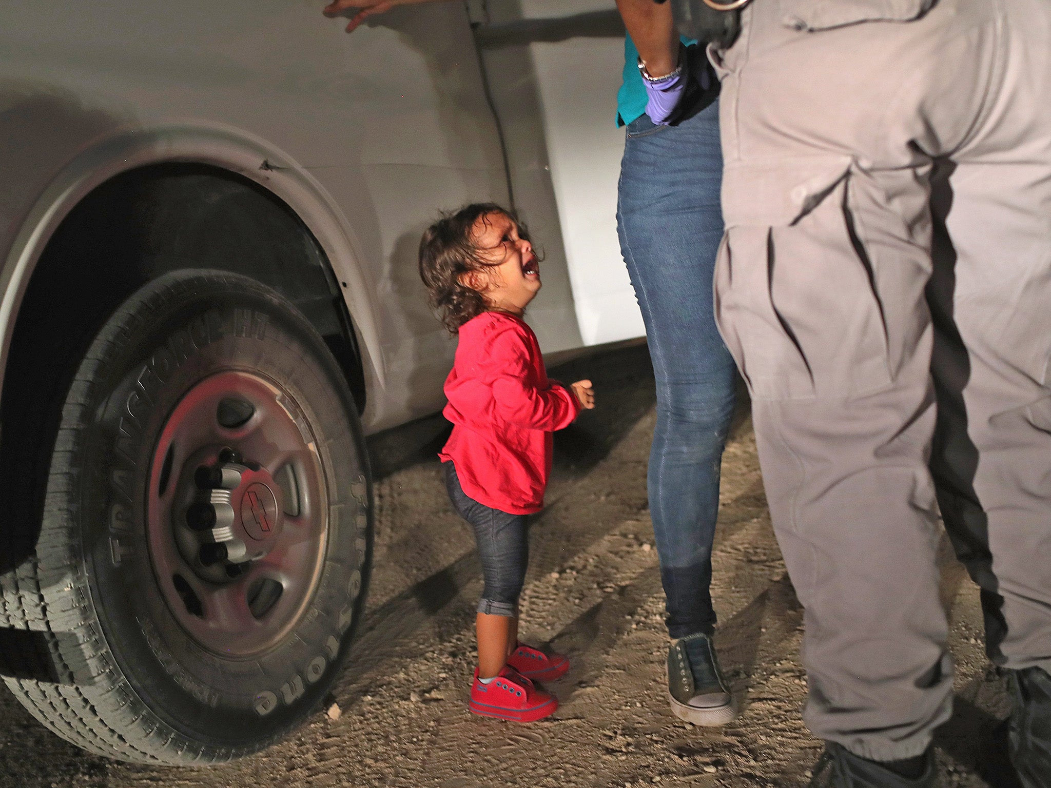 A two-year-old Honduran asylum seeker cries as her mother is searched and detained near the US-Mexico border