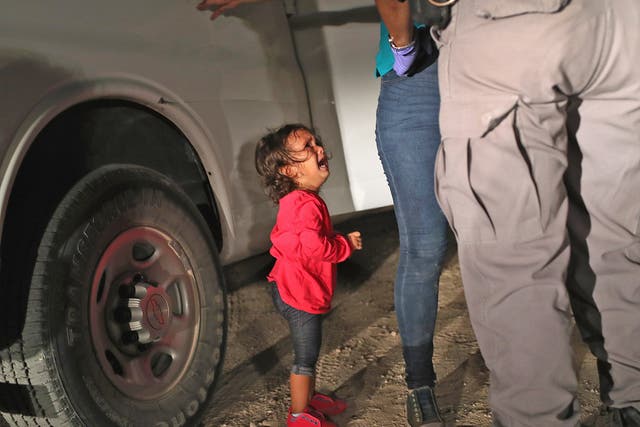 A two-year-old Honduran asylum seeker cries as her mother is searched and detained near the US-Mexico border on June 12, 2018 in McAllen, Texas