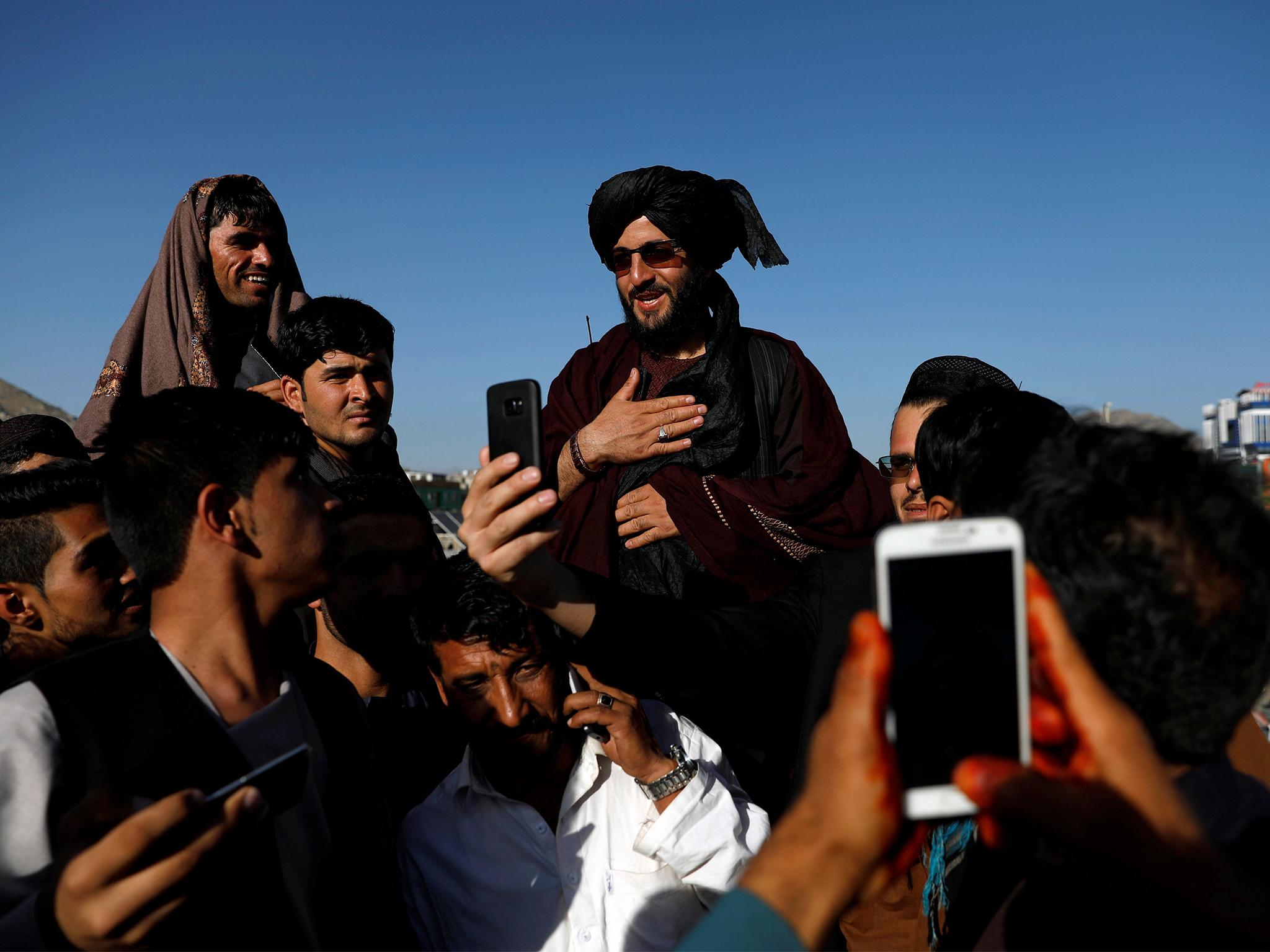 People take selfies with a Taliban fighter in Kabul during the Eid ceasefire