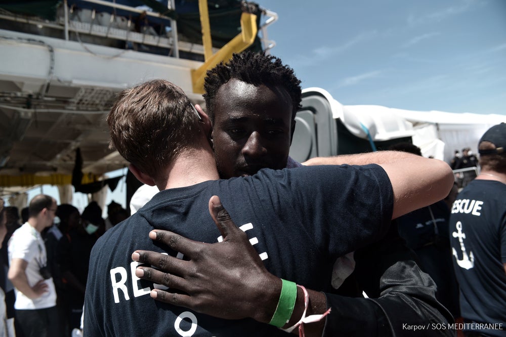 A migrant hugs a rescue team member before disembarking from the vessel Aquarius in Valencia