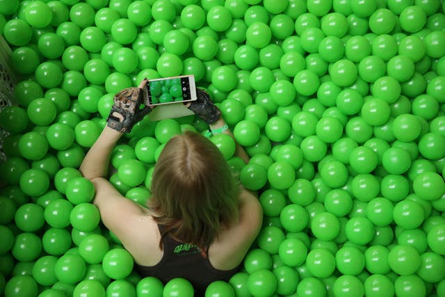 A participant uses her smartphone to photograph the green plastic balls pool she is sitting in at the annual re:publica conferences on their opening day on May 2, 2018 in Berlin, Germany