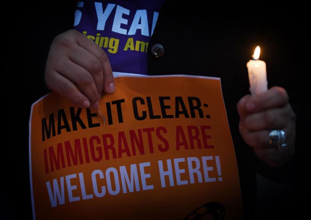 Migrant rights groups hold candles during a vigil to protest against US President Donald Trump's new crackdown on 'sanctuary cities', outside the City Hall in Los Angeles