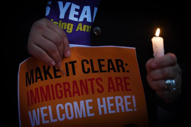 Migrant rights groups hold candles during a vigil to protest against US President Donald Trump's new crackdown on 'sanctuary cities', outside the City Hall in Los Angeles