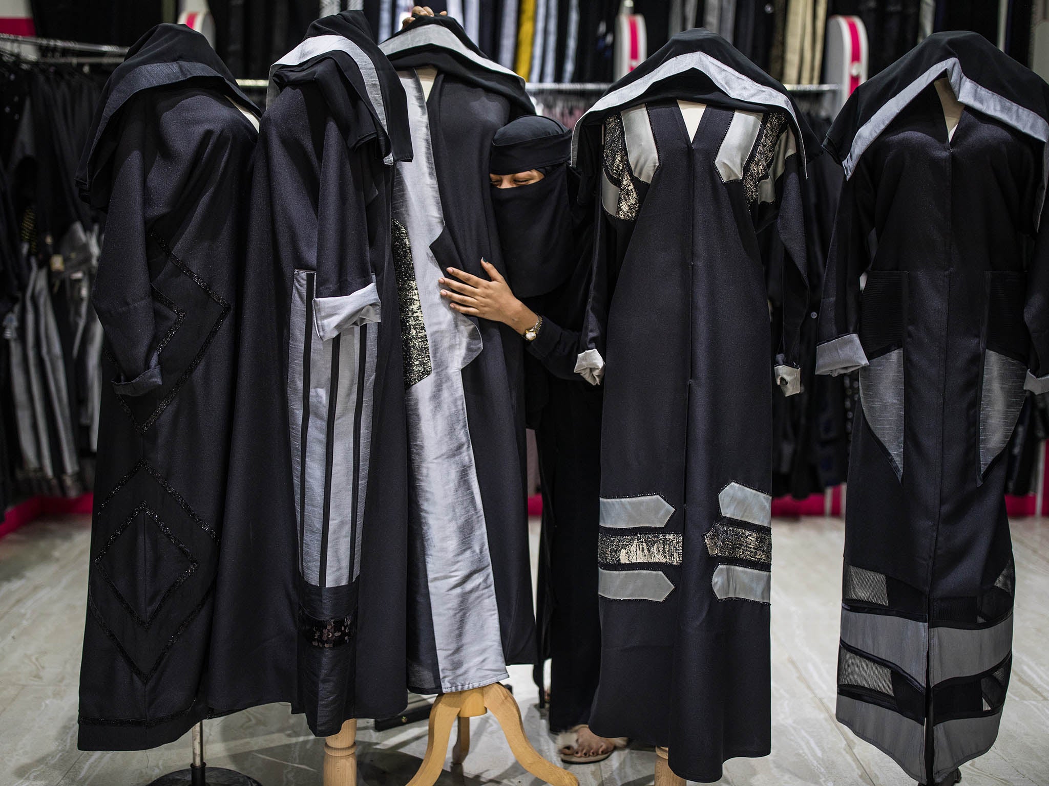 An employee at a shop in Riyadh, with the latest fashion in abayas that expresses a daring willingness to go beyond the existing constraints, but not so far as to stand out