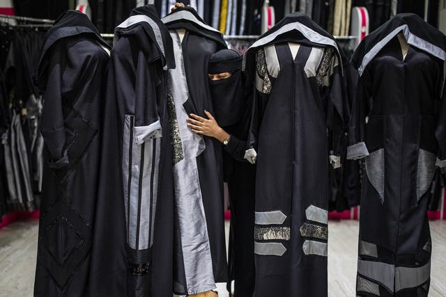 An employee at a shop in Riyadh, with the latest fashion in abayas that expresses a daring willingness to go beyond the existing constraints, but not so far as to stand out