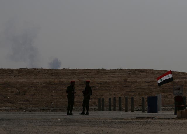 Smoke rises as Syrian army soldiers stand near a checkpoint in Deir Ezzor in this file photo from 21 September, 2017