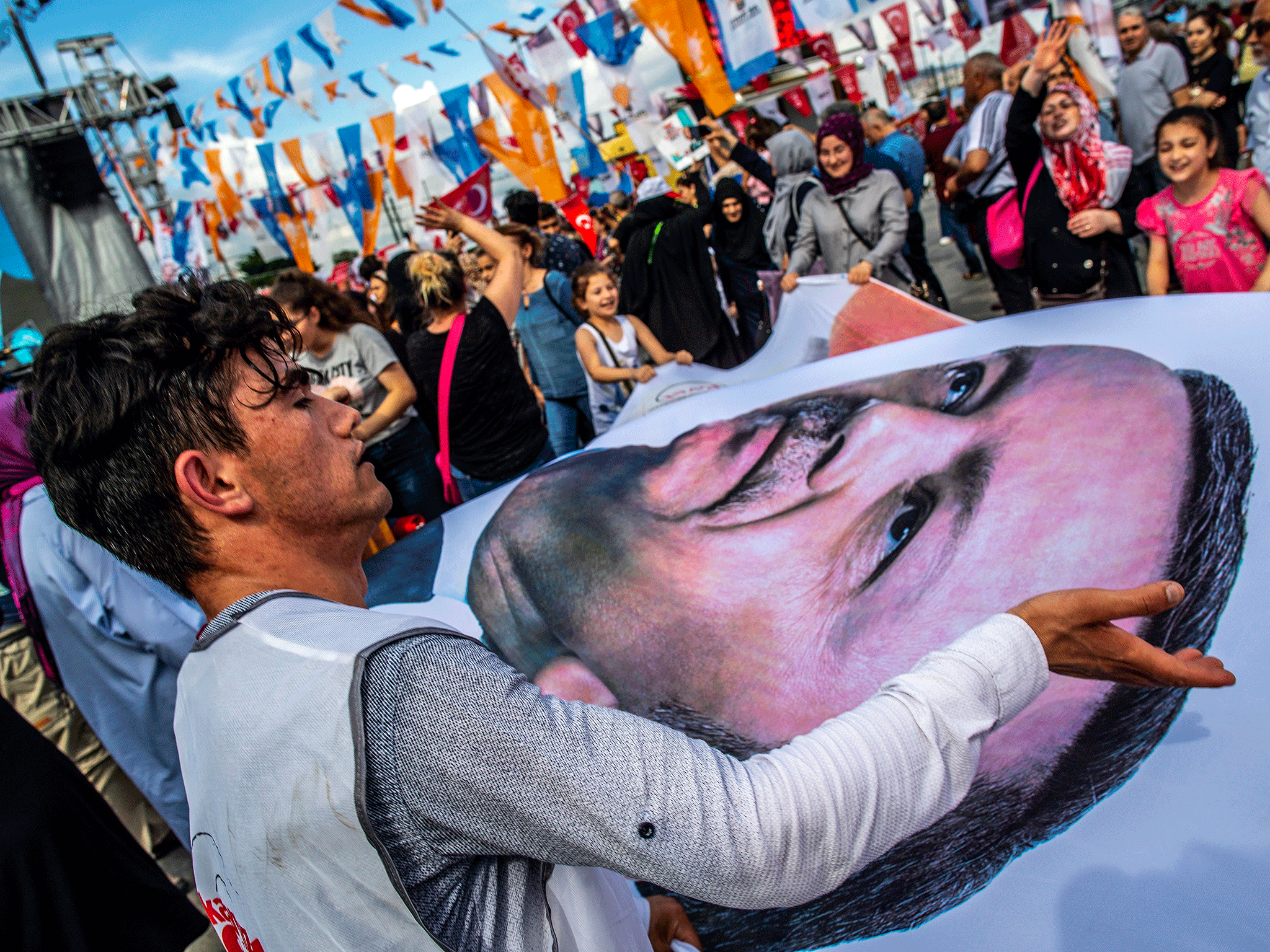 People wave a banner with a picture of Turkish President Recep Tayyip Erdogan during a gathering of supporters of his ruling Justice and Development Party (AKP) in Istanbul, Turkey, 19 June