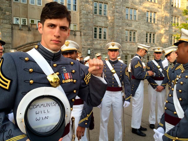 Spenser Rapone raises his left fist while showing a sign in a hat's inside after graduating from the US Military Academy at West Point