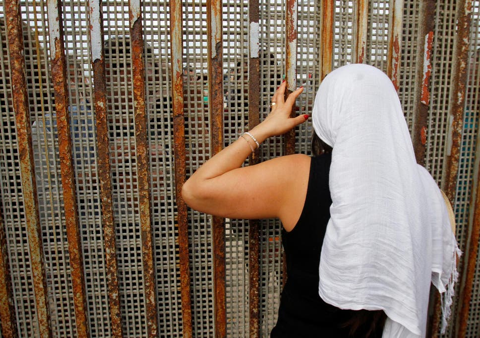 A Mexican woman talks with relatives through the fence that runs along the Mexico/US border in Tijuana, on Universal Children’s Day 2016 A Mexican woman talks with relatives through the fence that runs along the Mexico/US border in Tijuana, on Universal Children’s Day 2016