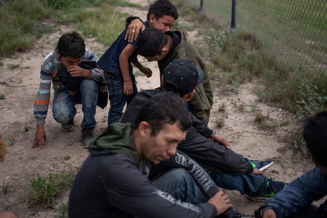 A four-year-old boy weeps in the arms of a family member as they are apprehended by border patrol agents after illegally crossing into the US border from Mexico, 2 May 2018