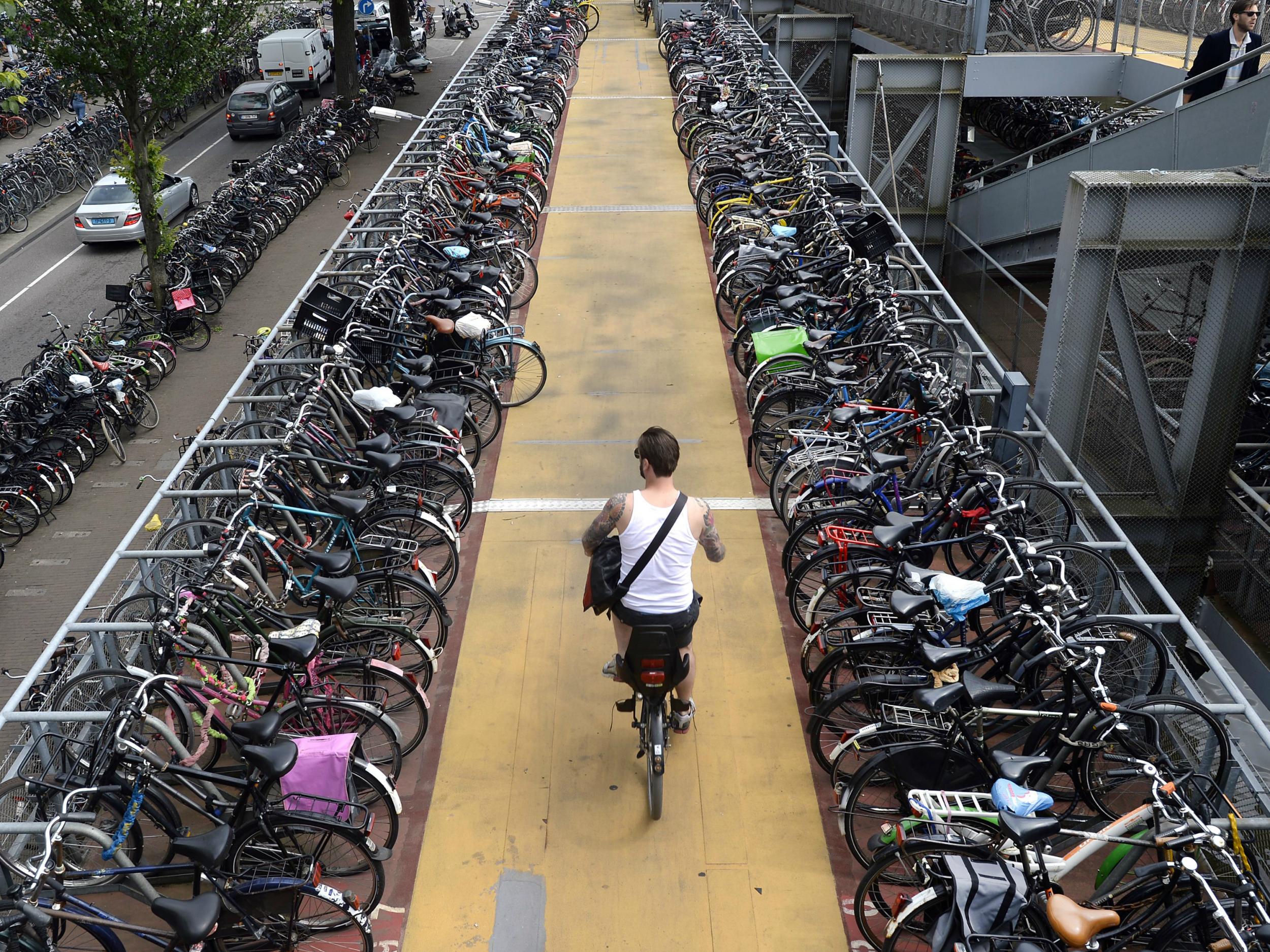 A man rides his bike down from a 3-story bike parking structure in Amsterdam. The government wants to encourage 200,000 more people to commute to work by bike