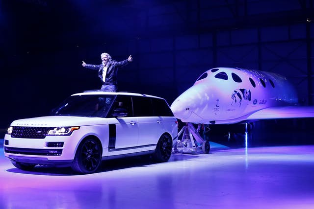 Sir Richard Branson stands in an SUV as it tows the Virgin Galactic SpaceShipTwo, named VSS Unity