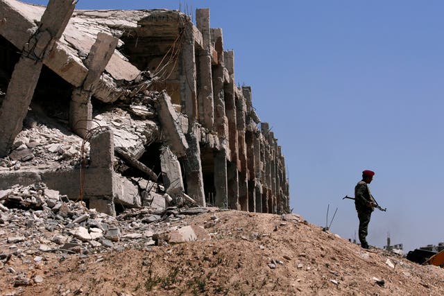 A Syrian government soldier stands guard near destroyed buildings in Jobar, Damascus