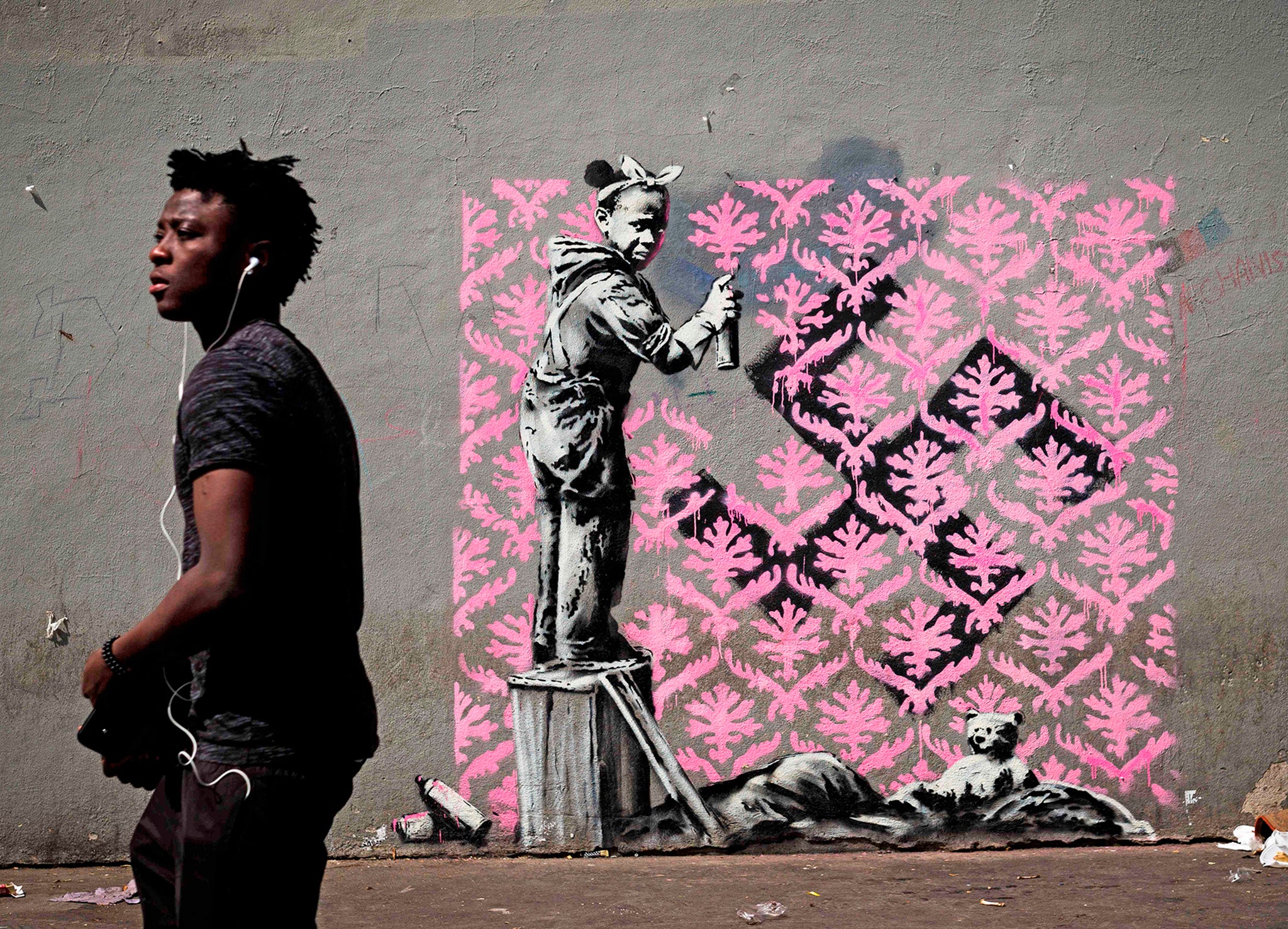 A man walks past a recent artwork by street artist Banksy in Paris
