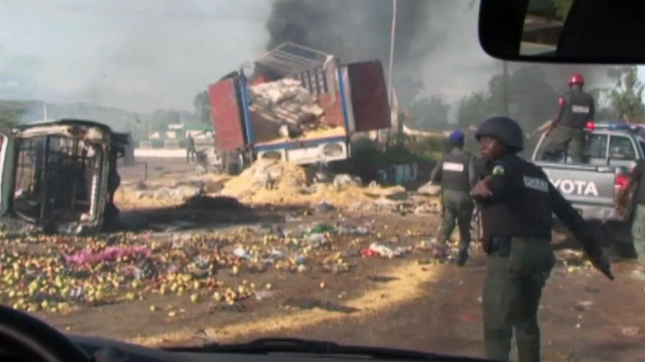 Destroyed vehicles and debris is strewn across the road as police attempt to restore calm in the town of Jos, Nigeria