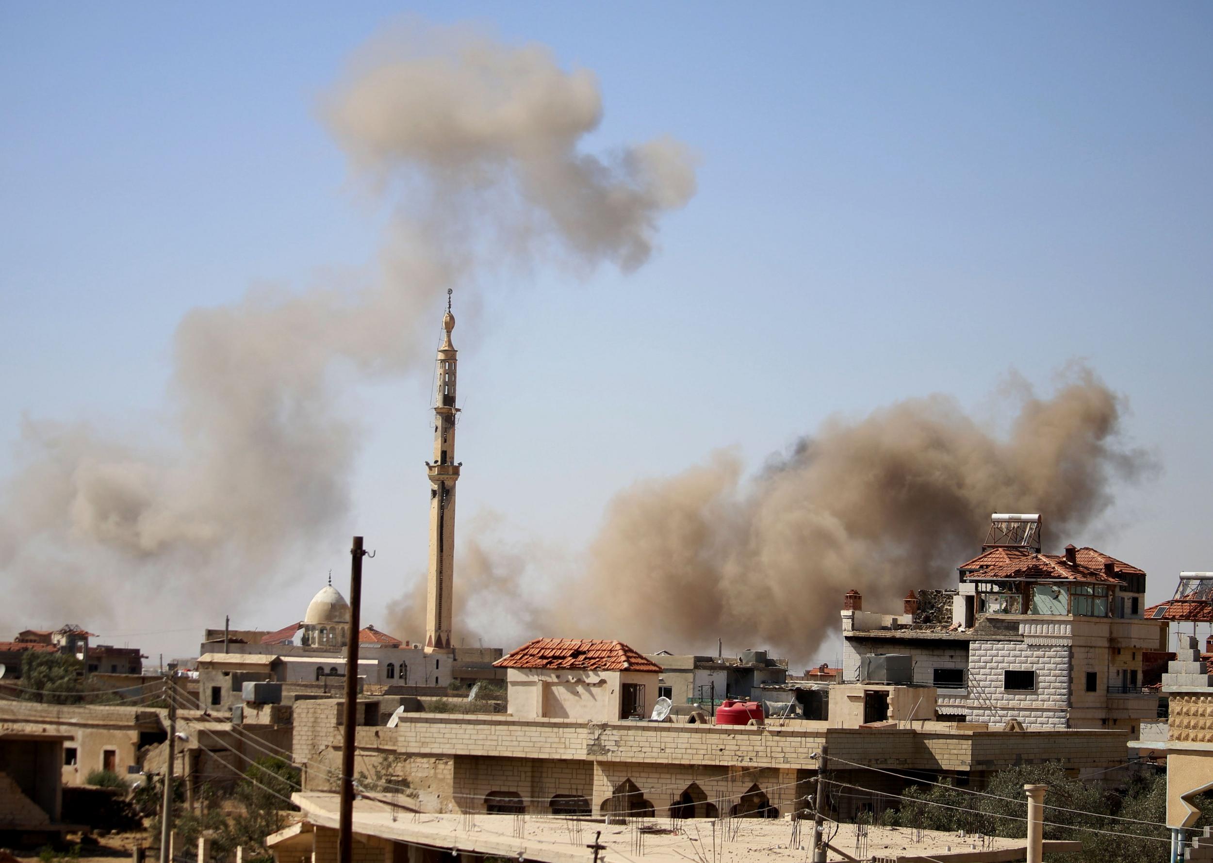Smoke rises above buildings during an airstrike by Syrian regime forces on the town of Busra al-Harir, east of Daraa