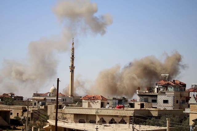 Smoke rises above buildings during an airstrike by Syrian regime forces on the town of Busra al-Harir, east of Daraa