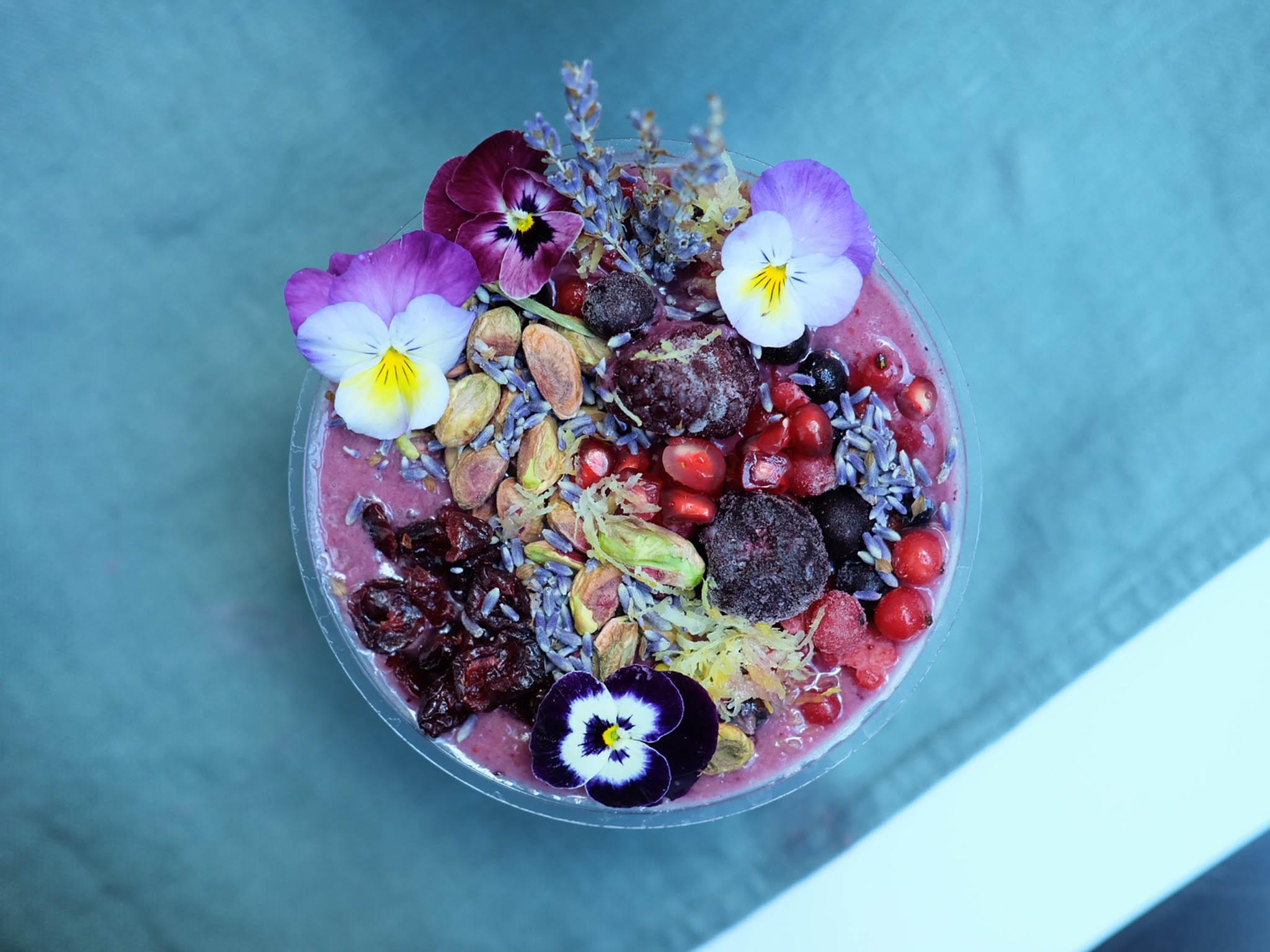 The lavender power smoothie bowl is made with blue matcha, berries, frozen pineapple and almond milk and sprinkled with seasonal toppings