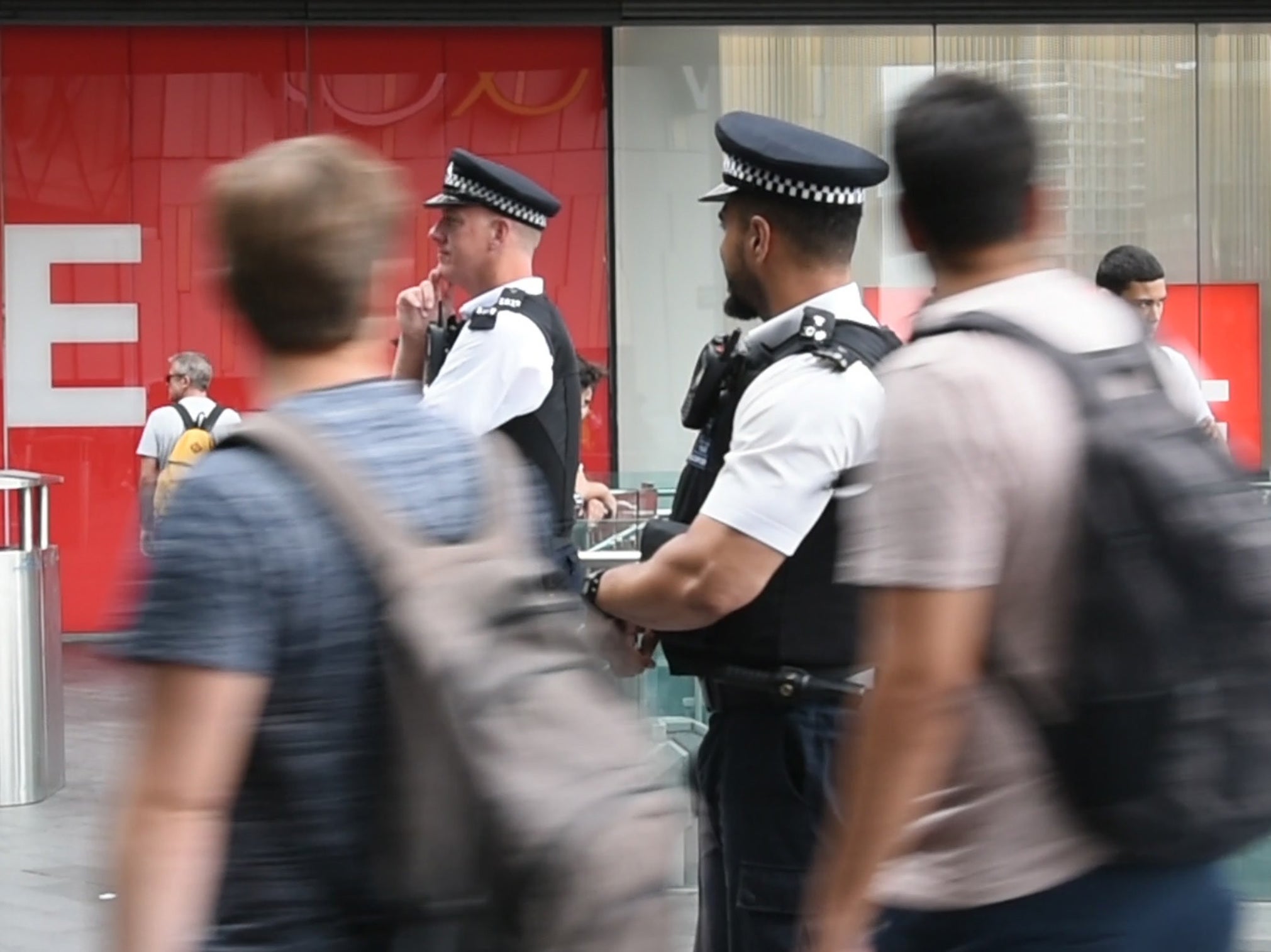 Police officers stand among shoppers in Stratford, East London.