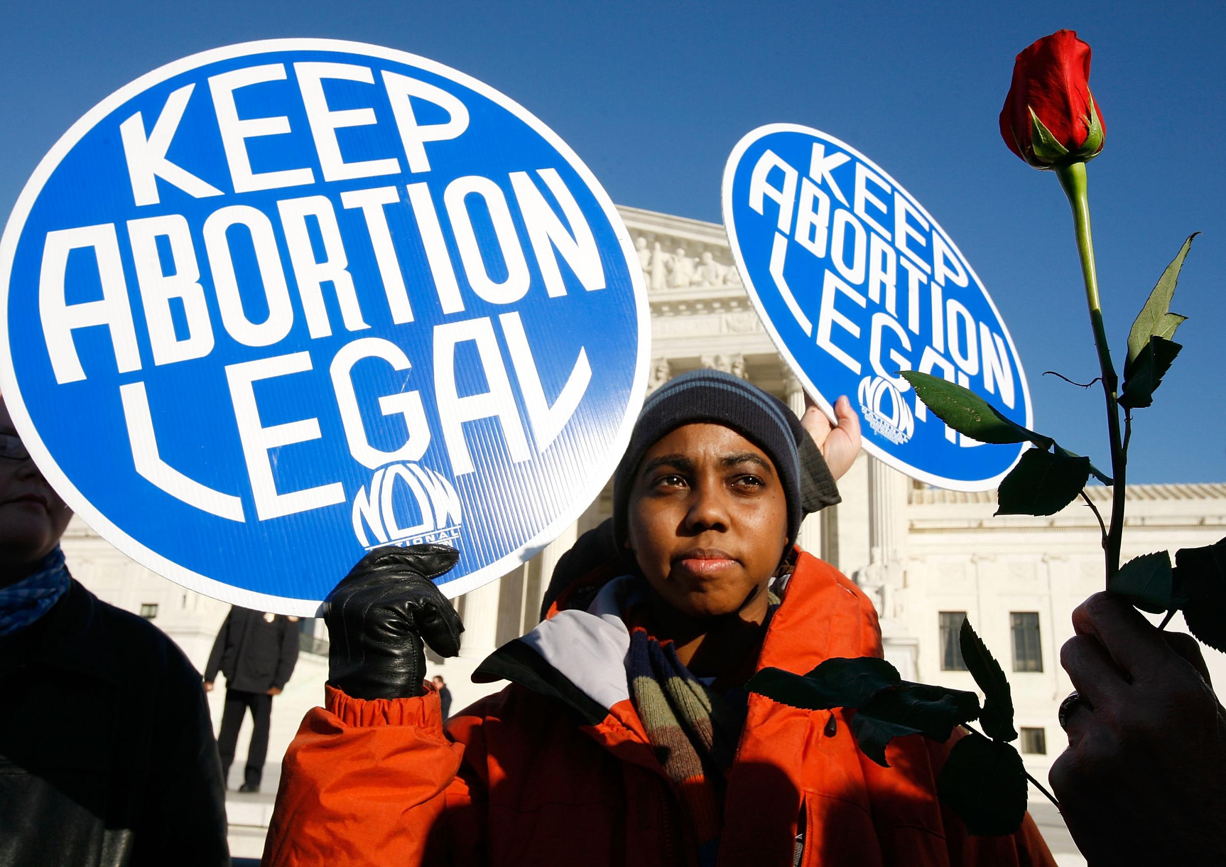 Local pro-choice activist Lisa King holds a sign in front of the U.S. Supreme Court as a pro-life activist holds a rose nearby during the annual 'March for Life' event