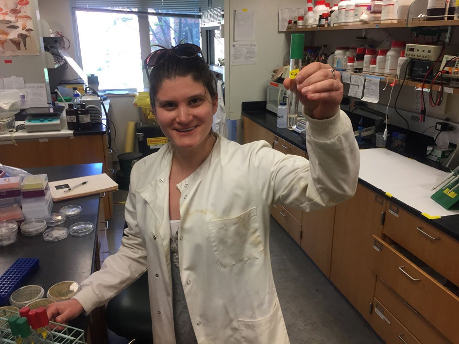 Morgan Vague holds up a test tube teeming with plastic-eating bacteria