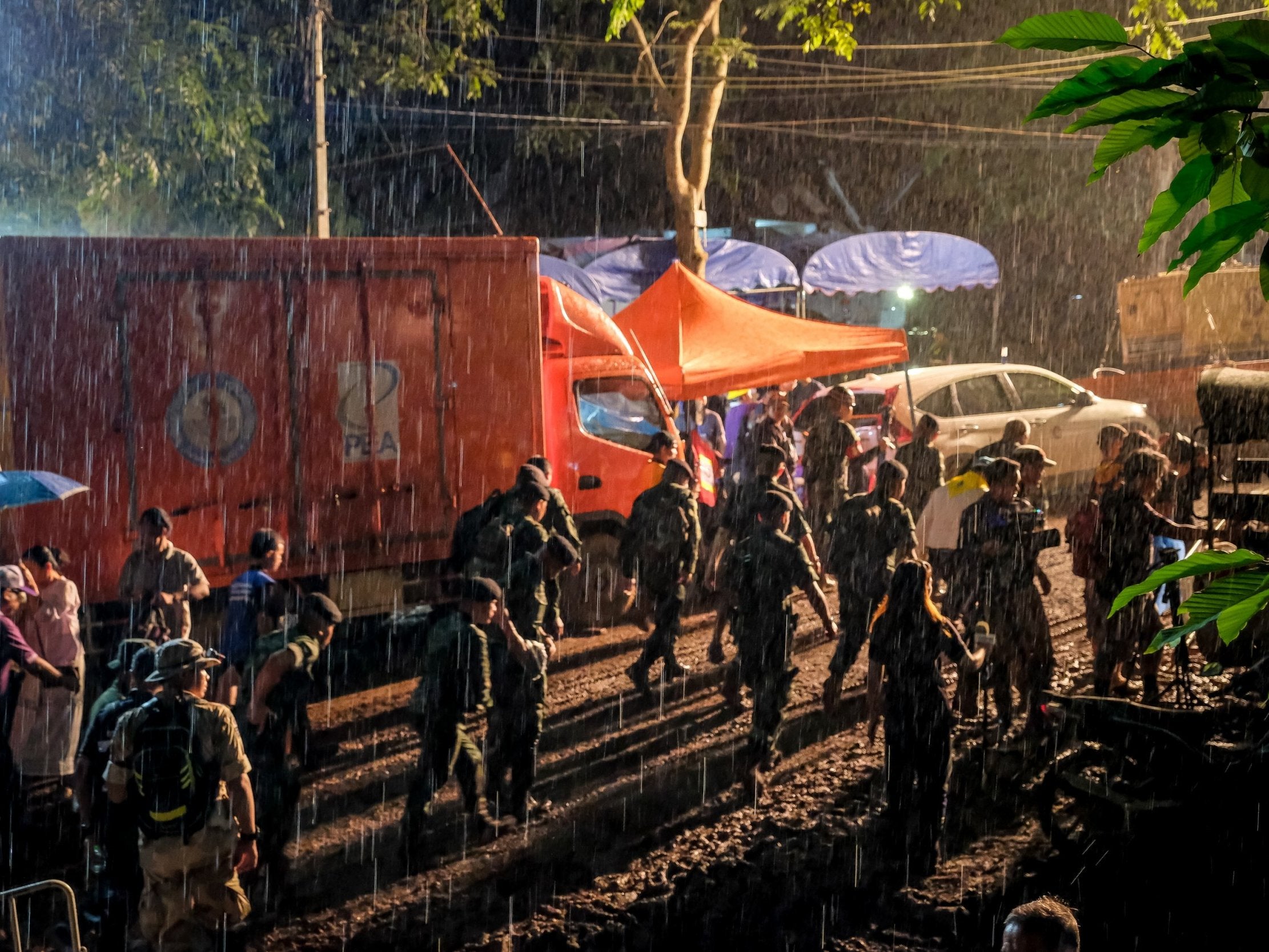 Policemen in the rain at Tham Luang Nang Non cave where the football team have gone missing
