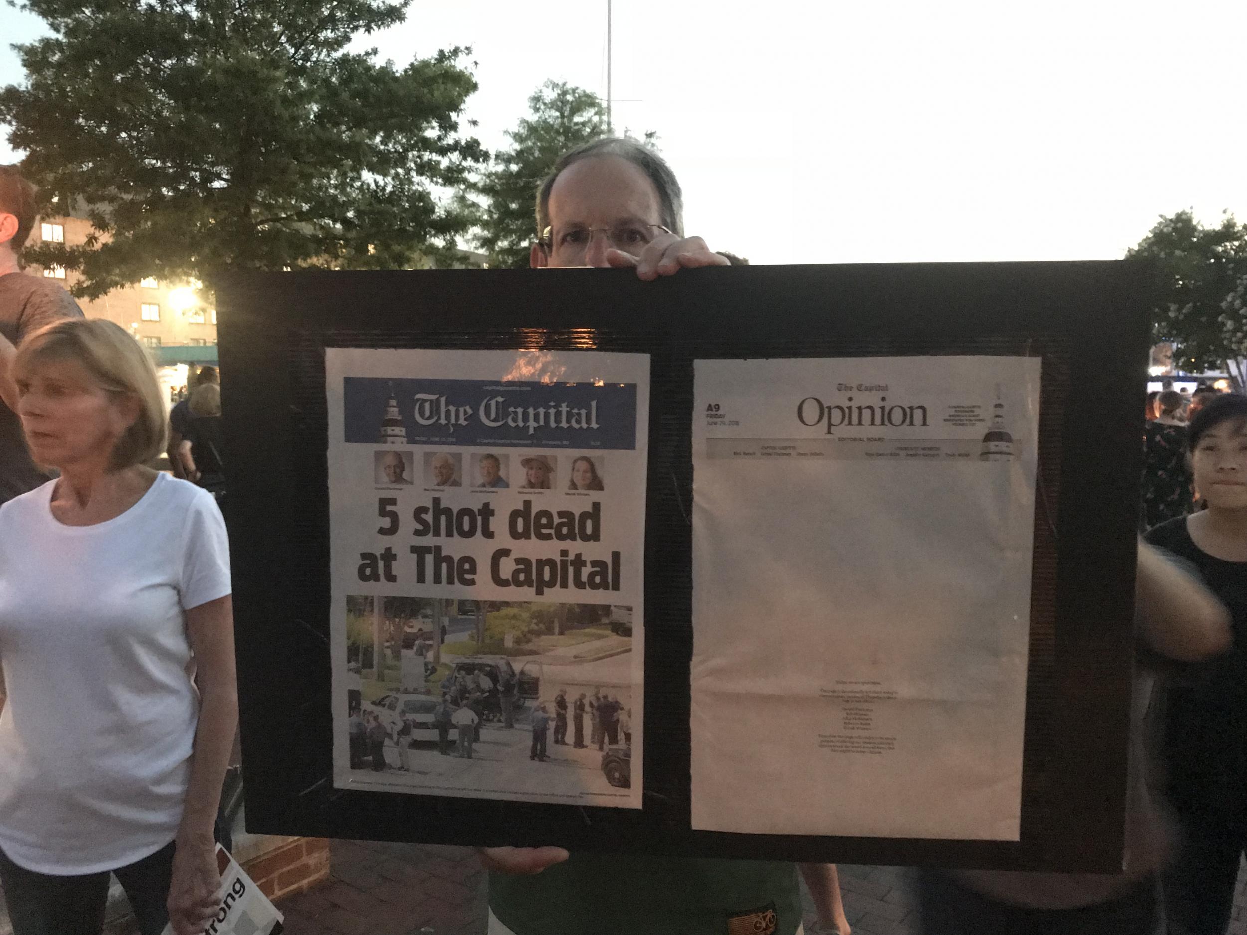 Annapolis resident John Korin holds up the front page of the Capital Gazette at a vigil