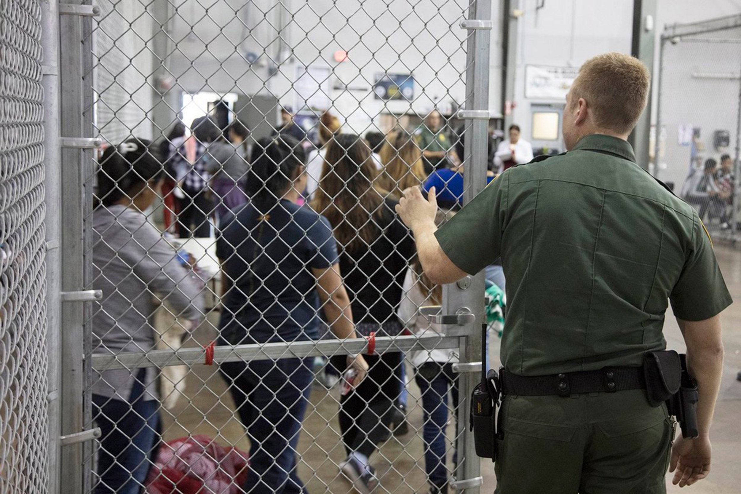 A US border patrol agent oversees migrants as they are processed at an immigrant detention centre