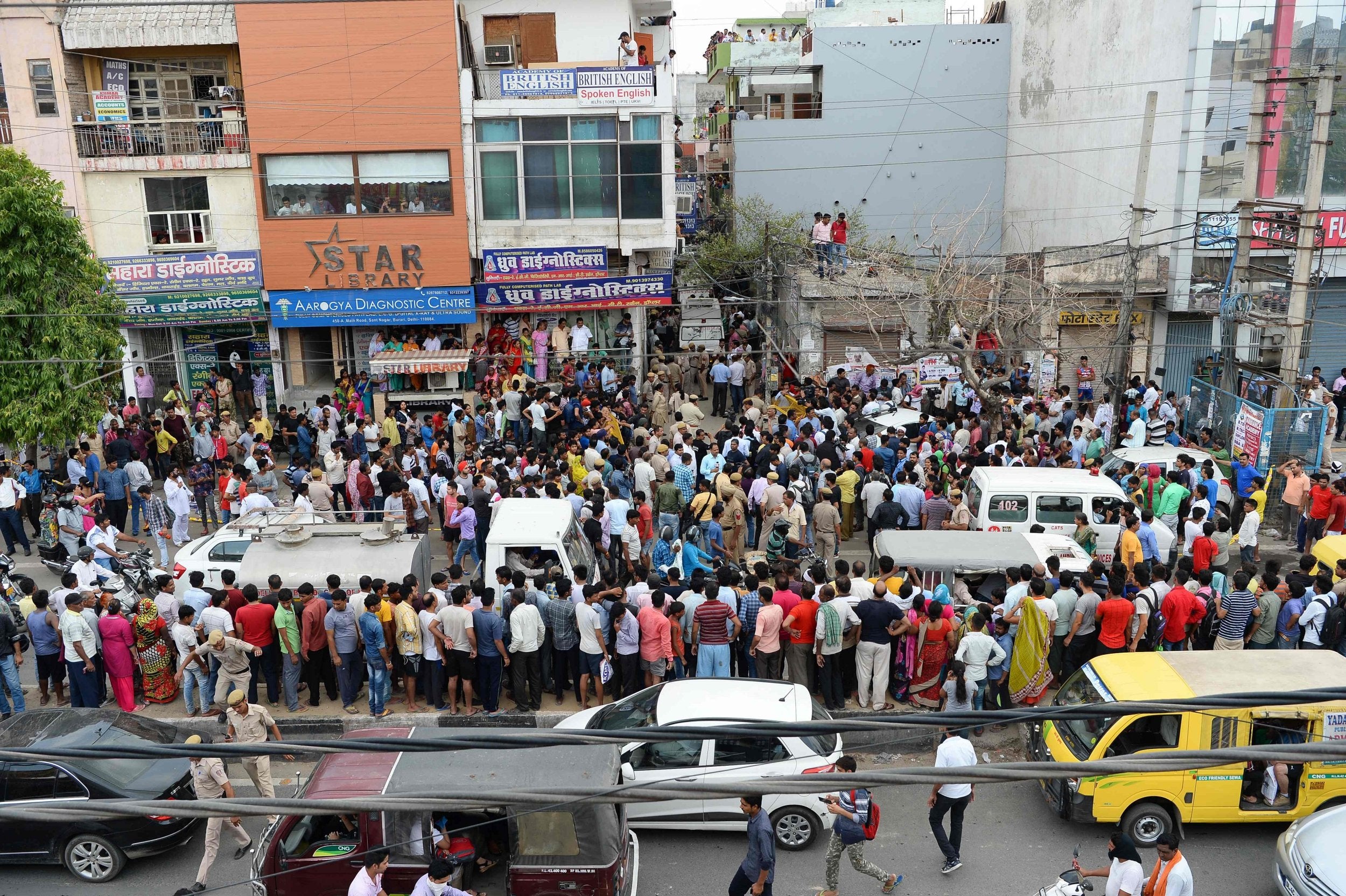 Onlookers gather along a road near the site where 11 family members were found dead inside their home in the neighbourhood of Burari in New Delhi