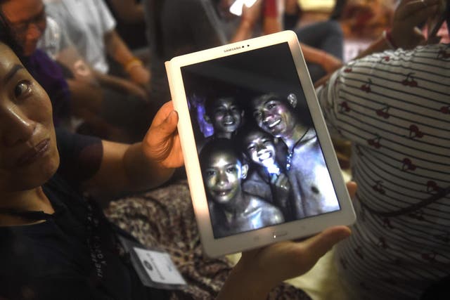 A happy family member shows the latest pictures of the missing boys taken by rescue divers inside Tham Luang cave when all members of children's football team and their coach were found alive