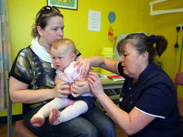 14-month-old Amelia Down sits on the lap of her mother Helen (L) as she receives the combined Measles Mumps and Rubella (MMR) vaccination at an MMR drop-in clinic at Neath Port Talbot Hospital near Swansea i
