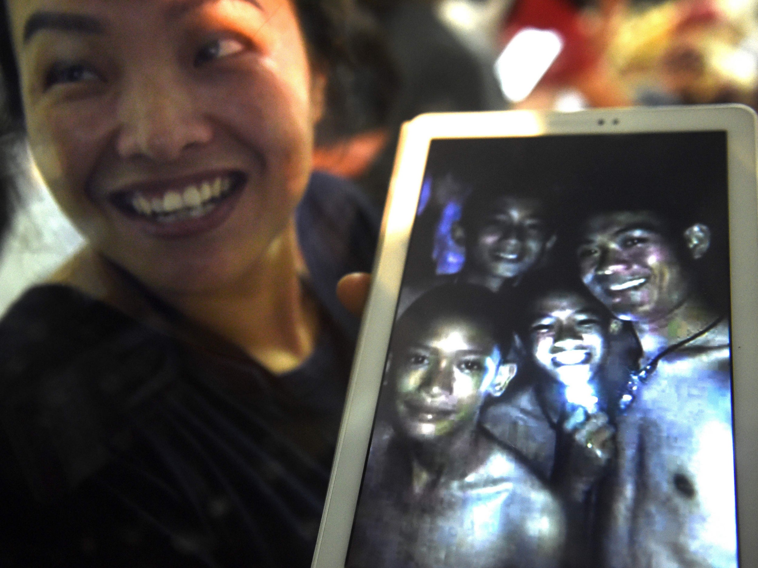 A family member shows a picture of four of the twelve missing boys