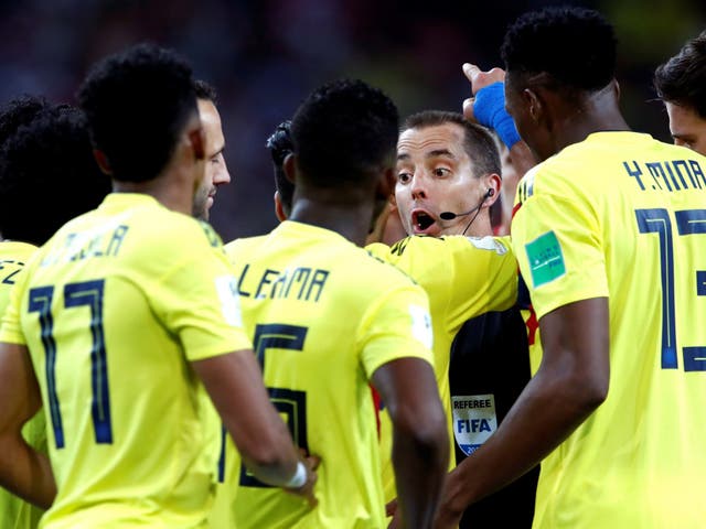 Colombia players surround referee Mark Geiger