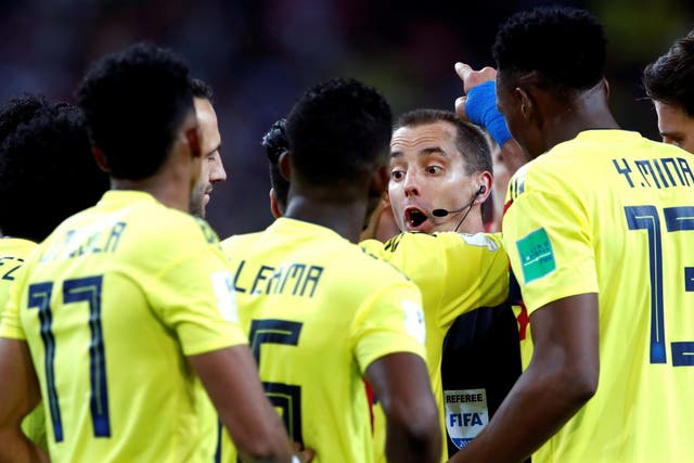 Colombia players surround referee Mark Geiger