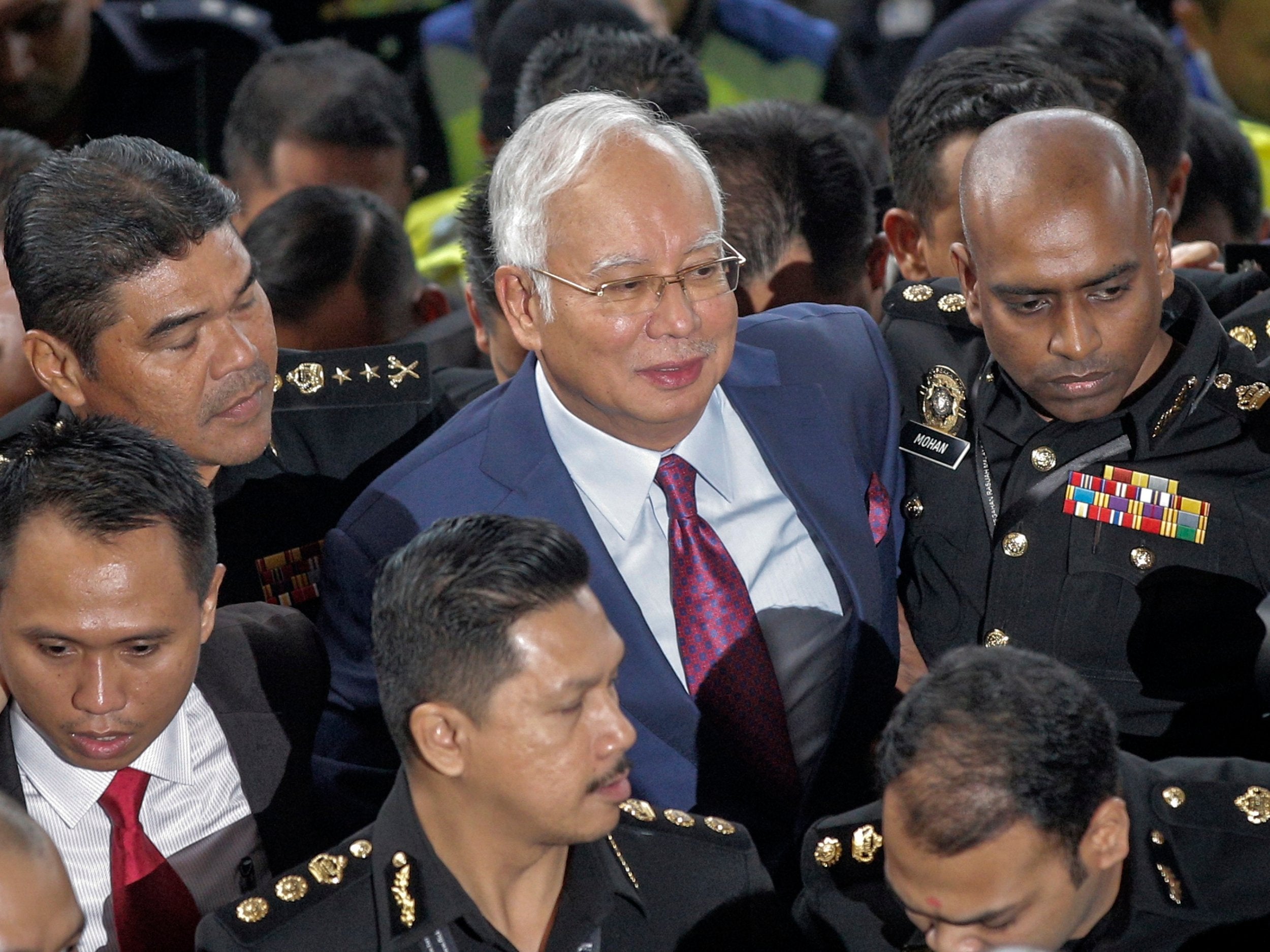 Former Malaysian prime minister Najib Razak is surrounded by police as he arrives at Kuala Lumpur High Court