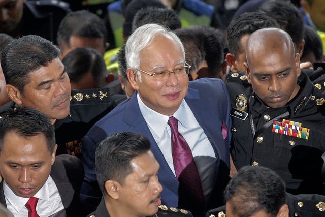 Former Malaysian prime minister Najib Razak is surrounded by police as he arrives at Kuala Lumpur High Court