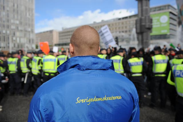 A supporter of the Sweden Democrats party stands behind a police line separating them from anti-racist protesters