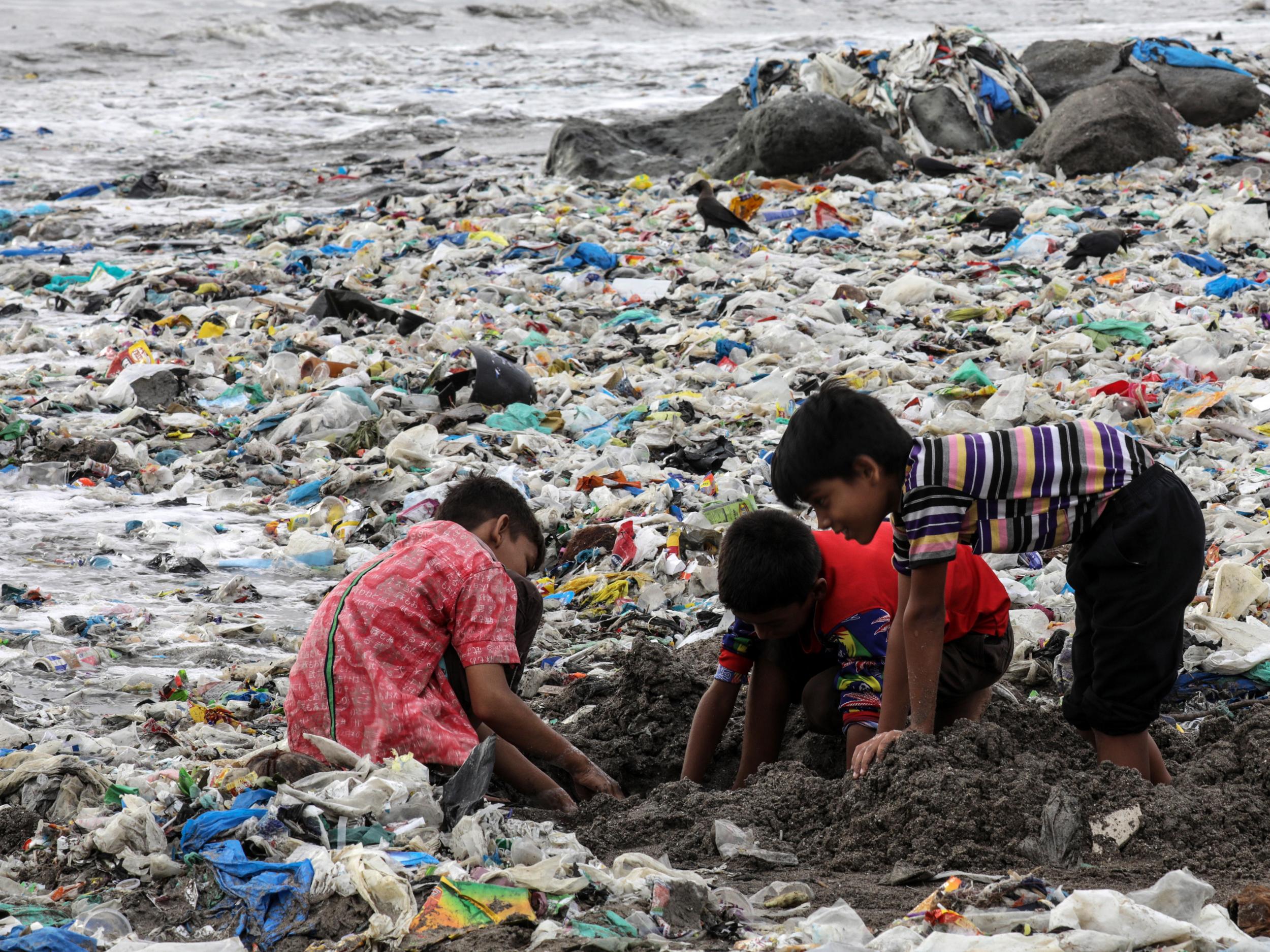 Indian children play amid leftovers and plastic waste at Mahim beach in Mumbai