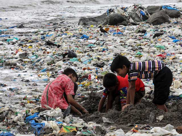 Indian children play amid leftovers and plastic waste at Mahim beach in Mumbai 