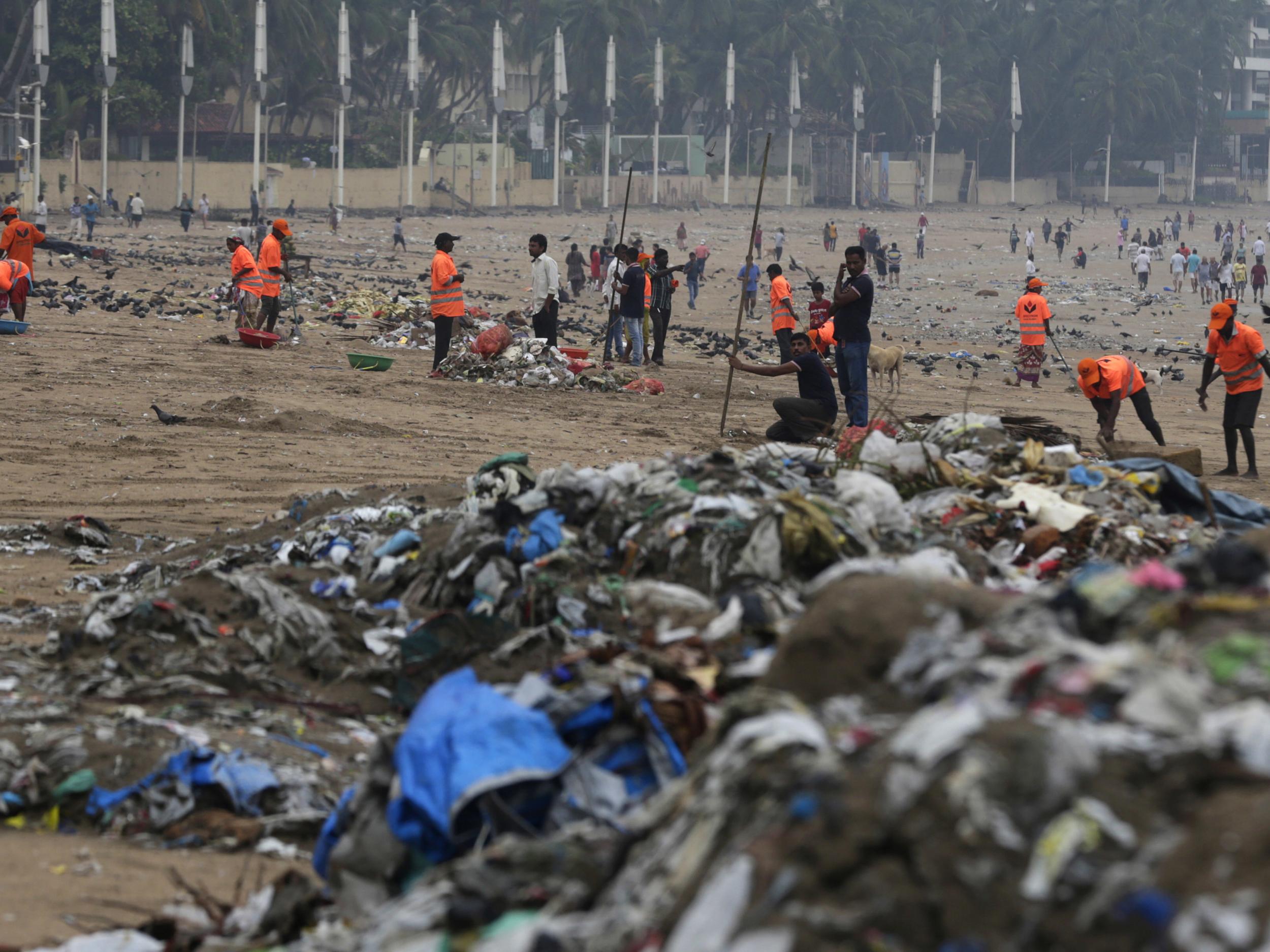 Municipal workers clean plastic and other rubbish on the shores of the Arabian Sea