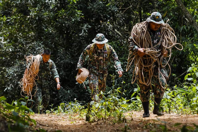 Thai park rangers carry ropes for a group of bird's nest collectors scouring a mountainside for openings to the trapped football team
